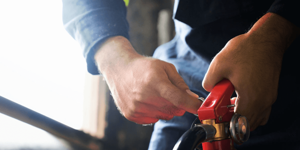Closeup of a fireman s hands pulling the pin from a fire extinguisher
